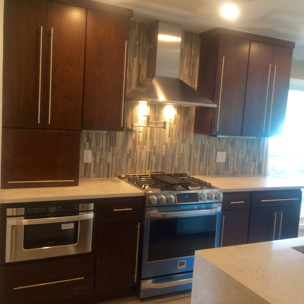 Example of a minimalist l-shaped ceramic tile eat-in kitchen design with an undermount sink, flat-panel cabinets, dark wood cabinets, marble countertops, multicolored backsplash, matchstick tile backsplash, stainless steel appliances and an island