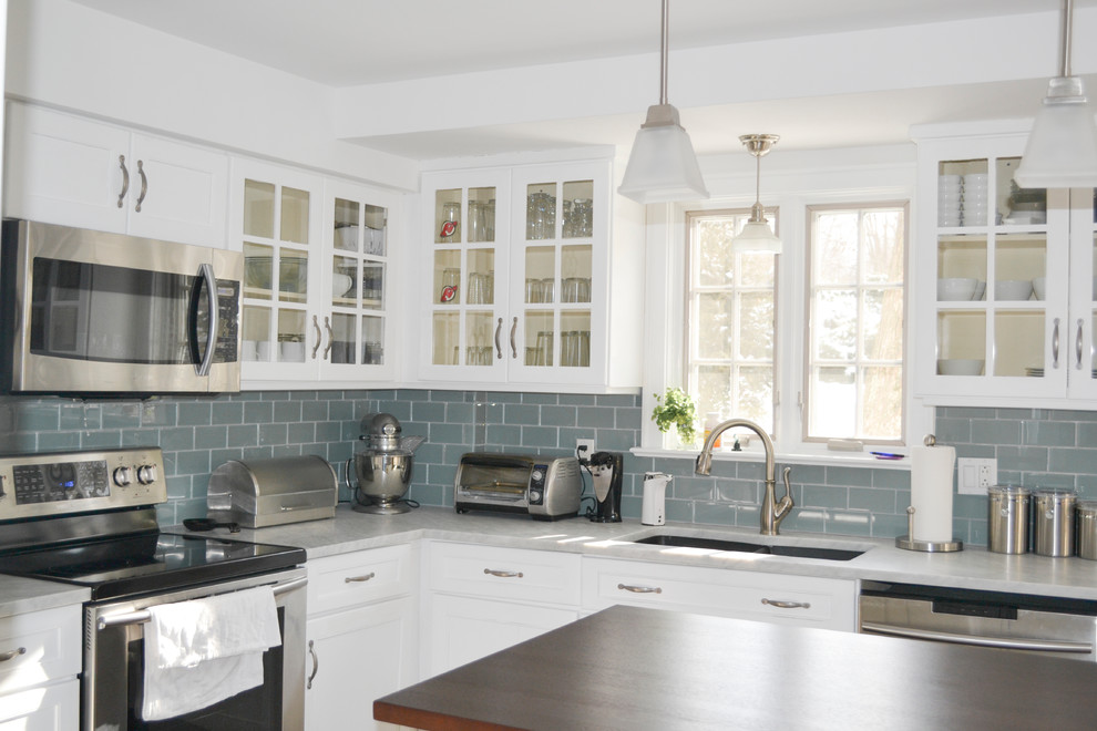 Transitional l-shaped dark wood floor kitchen photo with a double-bowl sink, shaker cabinets, white cabinets, marble countertops, blue backsplash, glass tile backsplash, stainless steel appliances and an island