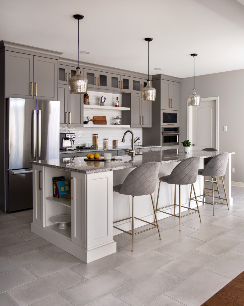 Large transitional l-shaped ceramic tile and gray floor open concept kitchen photo in Ottawa with a farmhouse sink, shaker cabinets, gray cabinets, granite countertops, white backsplash, subway tile backsplash, stainless steel appliances, an island and white countertops