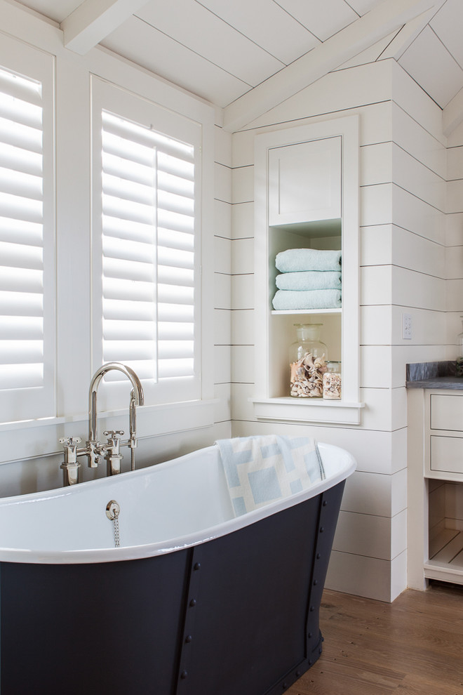 Inspiration for a large beach style master bathroom in Boston with white cabinets, a freestanding tub, white tile, ceramic tile, white walls, light hardwood floors and open cabinets.