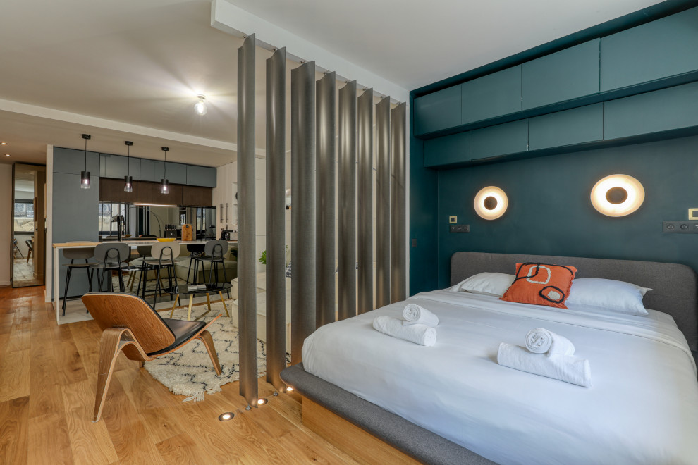 Kleines Modernes Hauptschlafzimmer ohne Kamin mit blauer Wandfarbe, hellem Holzboden und braunem Boden in Paris
