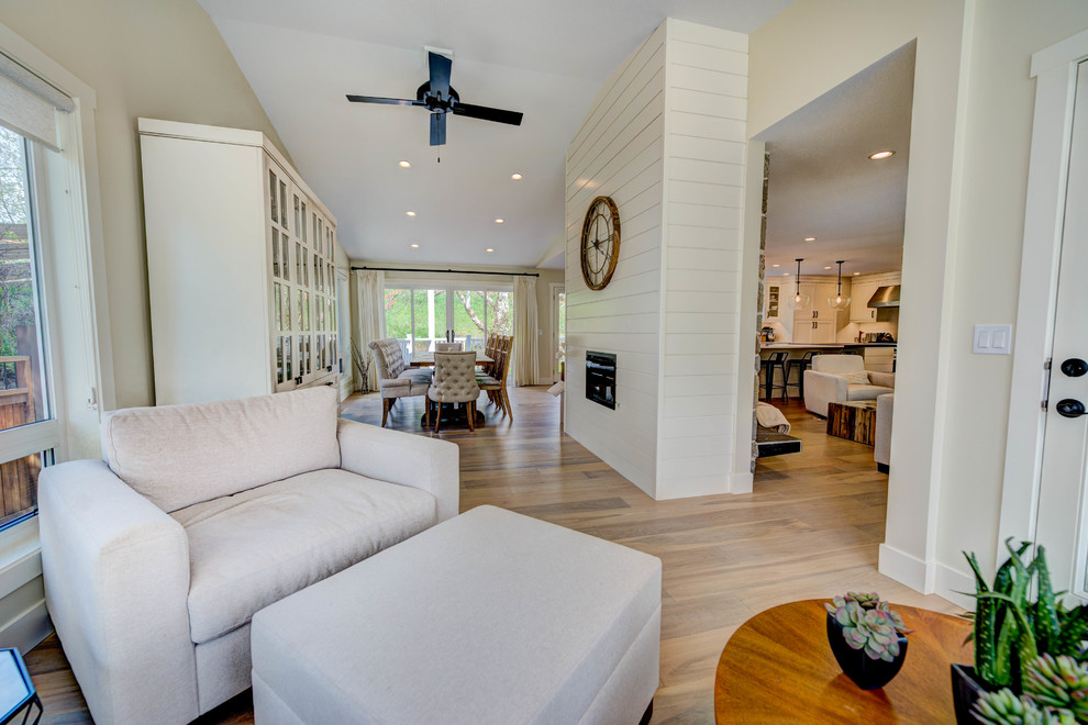 Mid-sized transitional l-shaped medium tone wood floor and beige floor eat-in kitchen photo in Vancouver with an undermount sink, shaker cabinets, white cabinets, quartz countertops, white backsplash, ceramic backsplash, stainless steel appliances and an island
