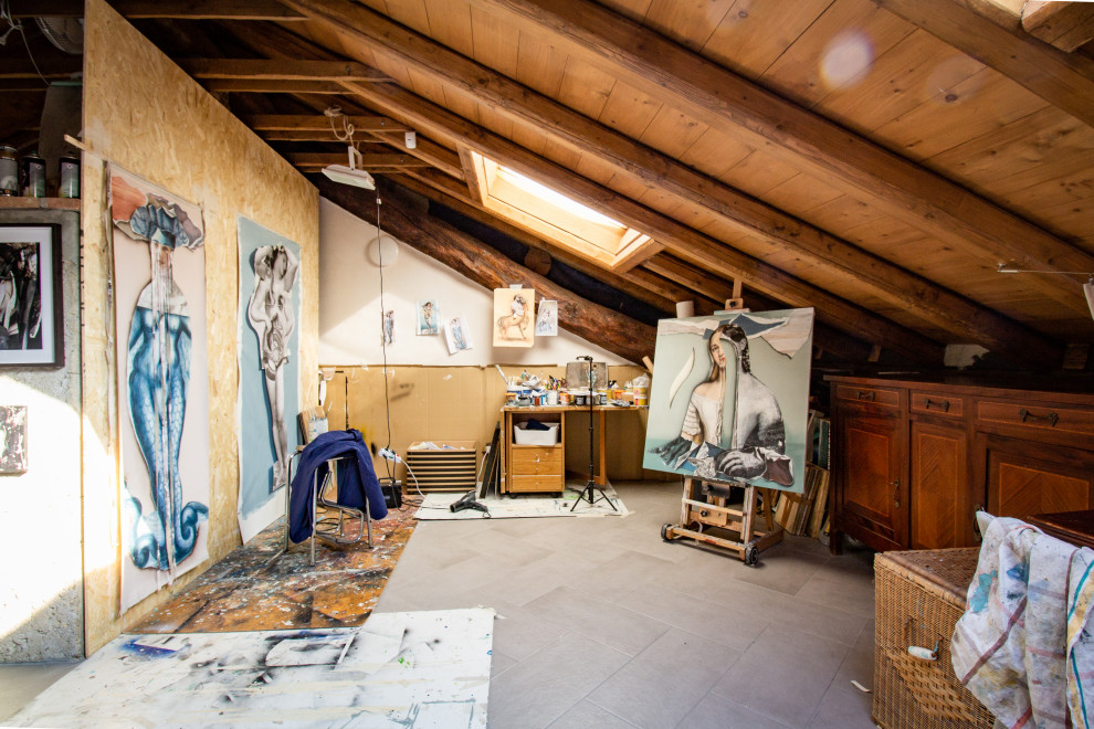 Photo of an expansive eclectic craft room in Other with pink walls, porcelain flooring, a wood burning stove, a freestanding desk, grey floors and exposed beams.