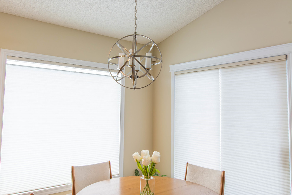 Mid-sized transitional l-shaped ceramic tile kitchen/dining room combo photo in Edmonton with a double-bowl sink, shaker cabinets, brown cabinets, quartz countertops, beige backsplash, glass tile backsplash, stainless steel appliances, an island, beige walls and no fireplace