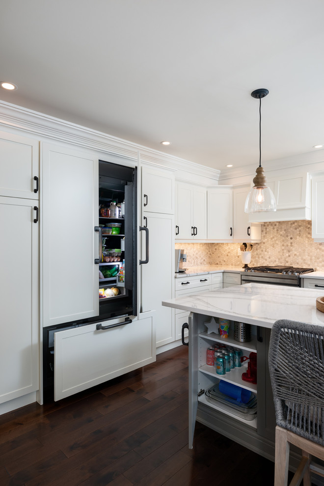 Example of a transitional dark wood floor and brown floor kitchen design with white cabinets, quartz countertops, paneled appliances, an island and white countertops