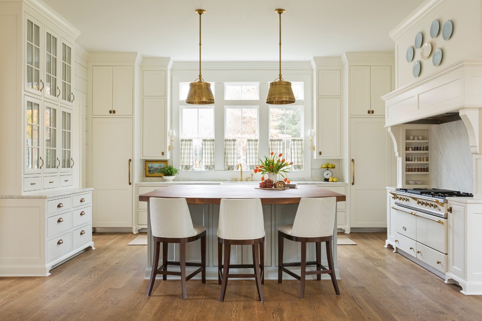 Inspiration for a large country single-wall separate kitchen in Little Rock with a farmhouse sink, recessed-panel cabinets, white cabinets, marble benchtops, grey splashback, stone slab splashback, panelled appliances, medium hardwood floors, with island, brown floor and white benchtop.