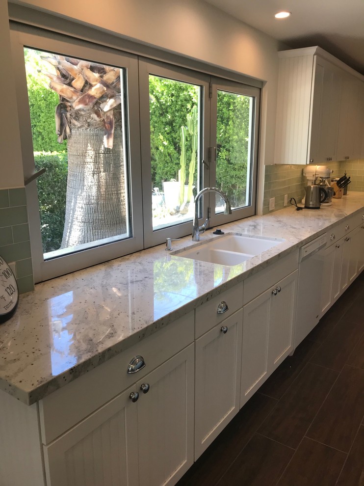 Large transitional l-shaped kitchen in Other with an undermount sink, white cabinets, glass tile splashback, porcelain floors, with island, brown floor, white benchtop, louvered cabinets, quartzite benchtops, grey splashback and stainless steel appliances.
