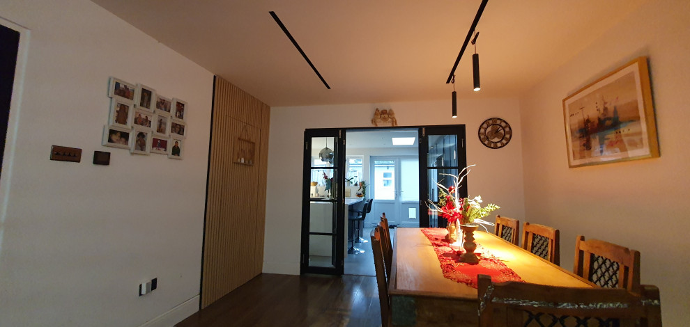 На фото: большая гостиная-столовая в современном стиле с белыми стенами, полом из ламината, разноцветным полом и деревянными стенами без камина
