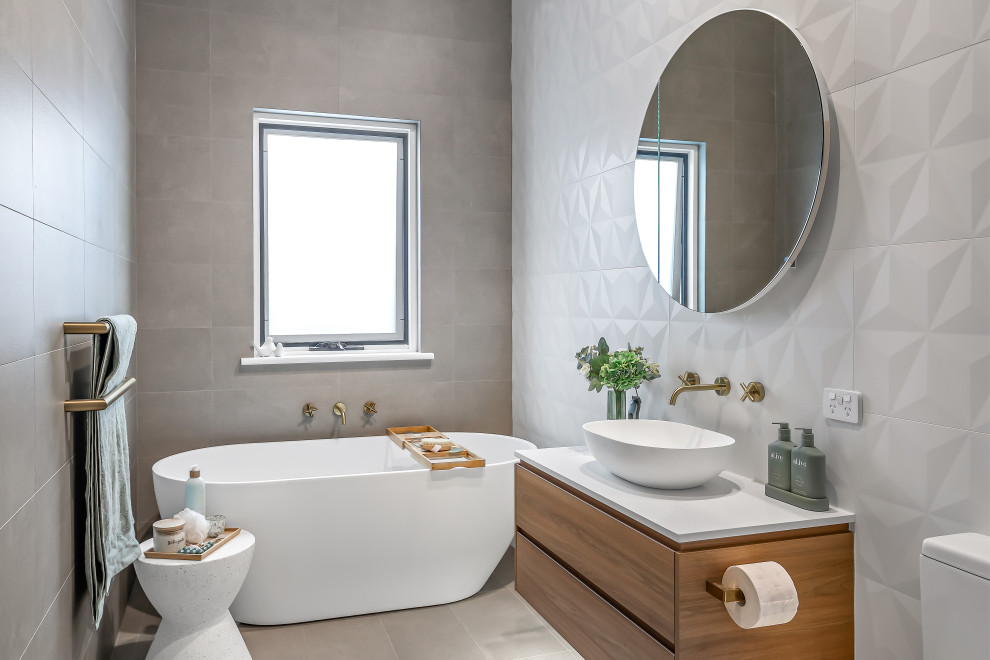 Design ideas for a contemporary bathroom in Adelaide with medium wood cabinets, a freestanding tub, a one-piece toilet, gray tile, ceramic tile, white walls, ceramic floors, a vessel sink, engineered quartz benchtops, grey floor, white benchtops, a single vanity and a floating vanity.