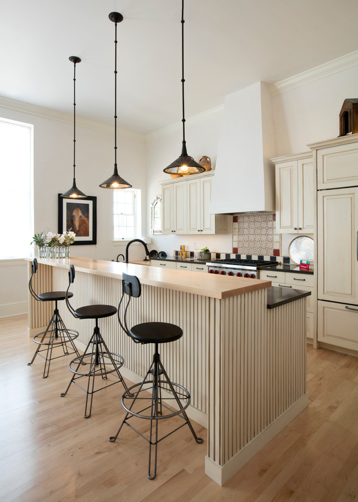 Inspiration for a mid-sized traditional l-shaped open plan kitchen in Albuquerque with raised-panel cabinets, beige cabinets, beige splashback, panelled appliances, light hardwood floors, with island, an undermount sink, granite benchtops, ceramic splashback and black benchtop.