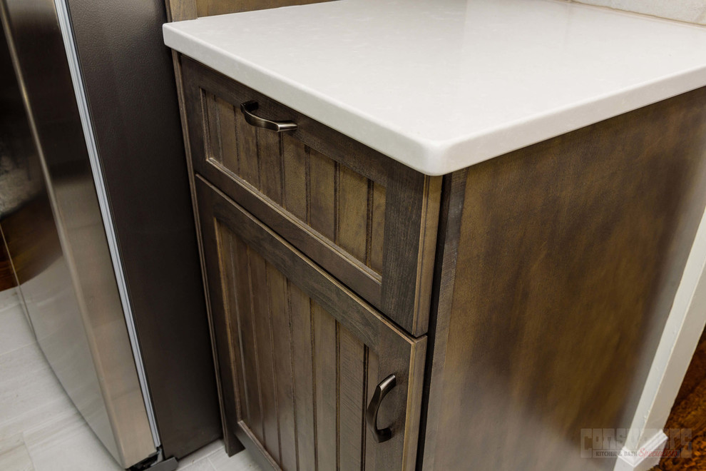 Eat-in kitchen - mid-sized l-shaped eat-in kitchen idea in New York with a farmhouse sink, recessed-panel cabinets, brown cabinets, quartz countertops, beige backsplash, porcelain backsplash, stainless steel appliances, an island and white countertops