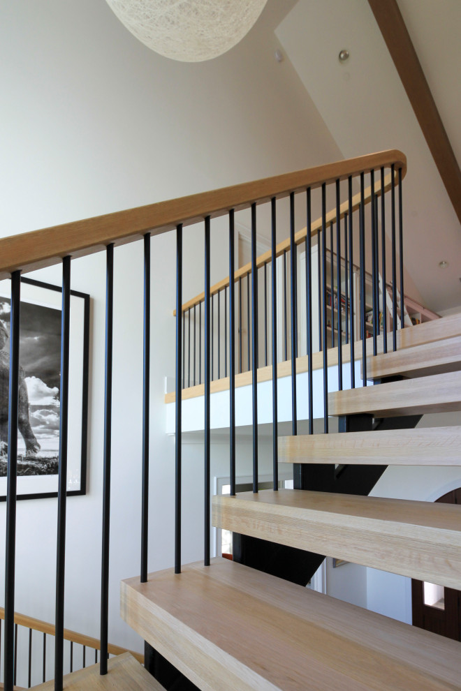 Пример оригинального дизайна: огромная лестница на больцах в стиле модернизм с деревянными ступенями, перилами из смешанных материалов и стенами из вагонки