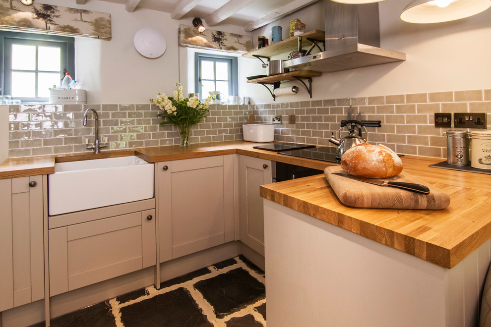 Photo of a small country u-shaped open plan kitchen in Cornwall with recessed-panel cabinets, brown cabinets, wood benchtops, grey splashback, ceramic splashback, bamboo floors, no island and black floor.