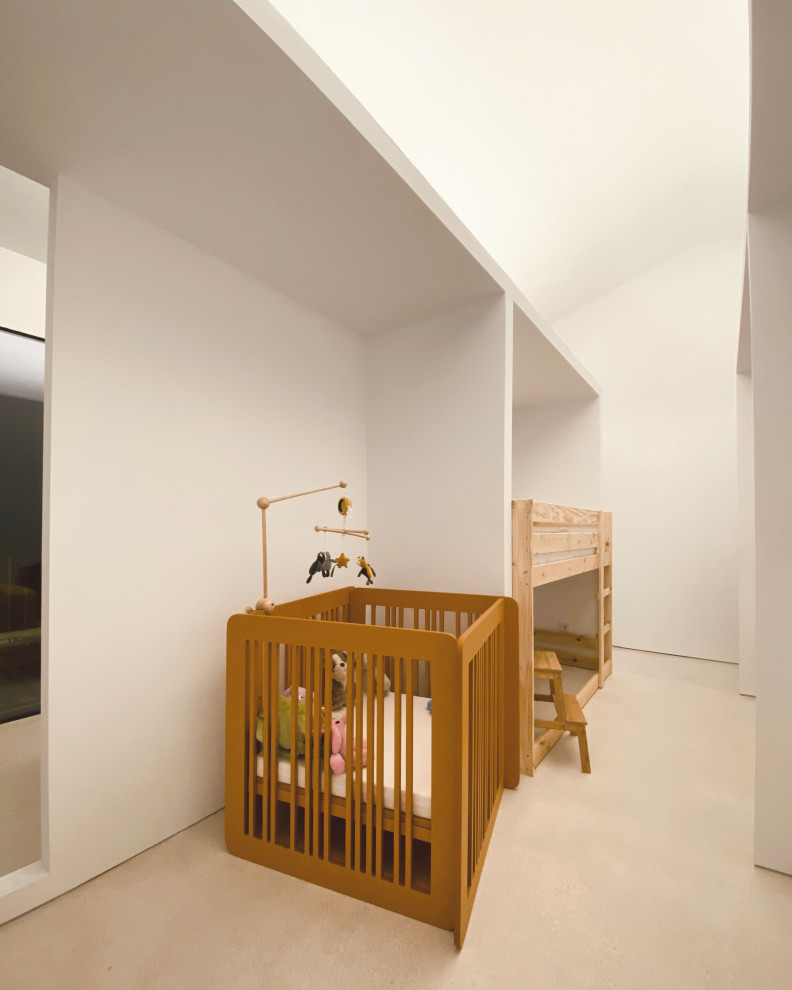 На фото: нейтральная детская среднего размера в стиле лофт с спальным местом, белыми стенами, бетонным полом и серым полом для ребенка от 1 до 3 лет