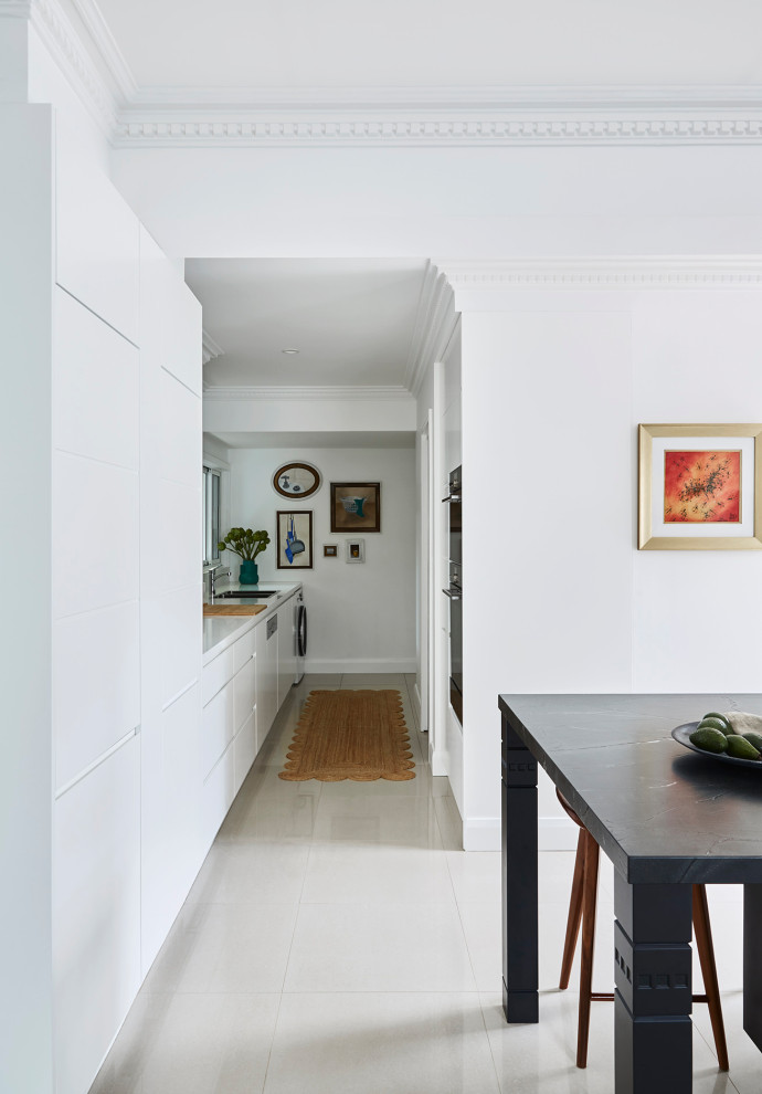 Photo of a large retro l-shaped open plan kitchen in Sydney with flat-panel cabinets, white cabinets, granite worktops, white splashback, cement flooring, an island, white floors and black worktops.