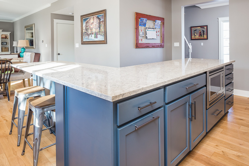 Eat-in kitchen - large transitional l-shaped eat-in kitchen idea with white cabinets, quartzite countertops, gray backsplash, glass tile backsplash, stainless steel appliances and an island