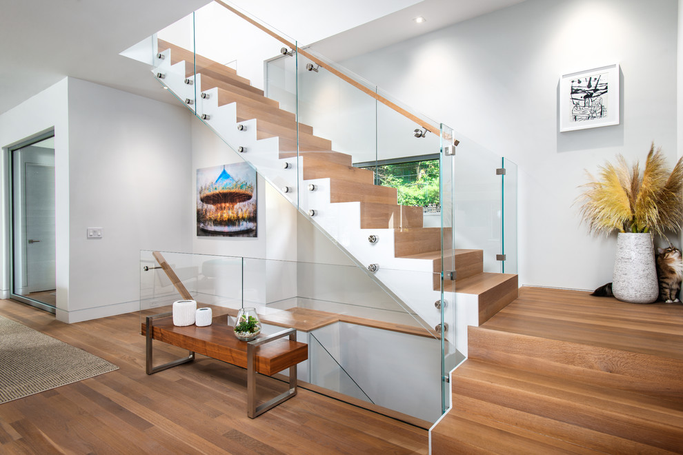 This is an example of a mid-sized contemporary wood l-shaped staircase in New York with wood risers and glass railing.