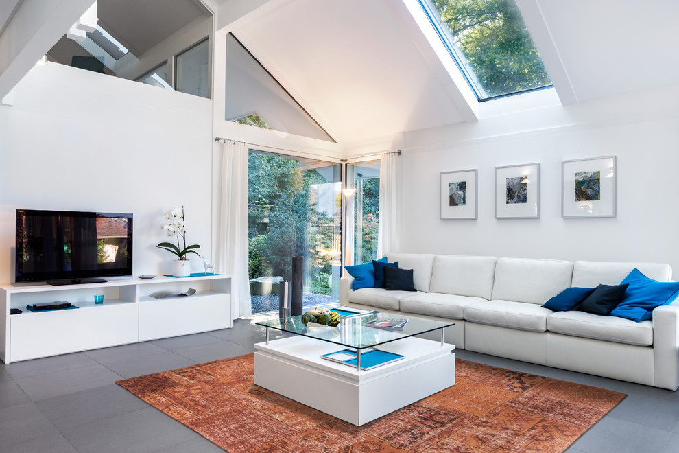 Contemporary living room in London with white walls, a freestanding tv and grey floor.