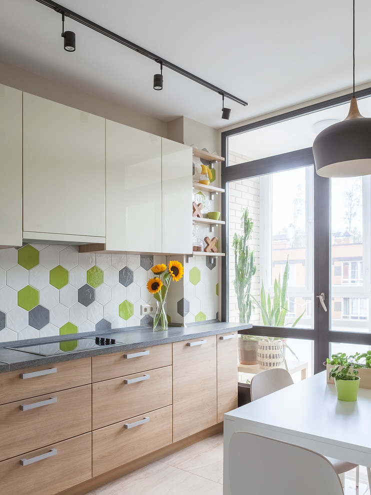 Photo of a scandinavian separate kitchen in Moscow with flat-panel cabinets, light wood cabinets, multi-coloured splashback, beige floor and grey benchtop.