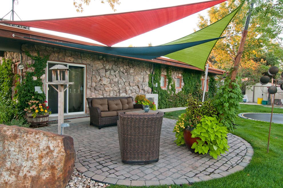 Photo of an eclectic backyard patio in Boise with a container garden, concrete pavers and an awning.