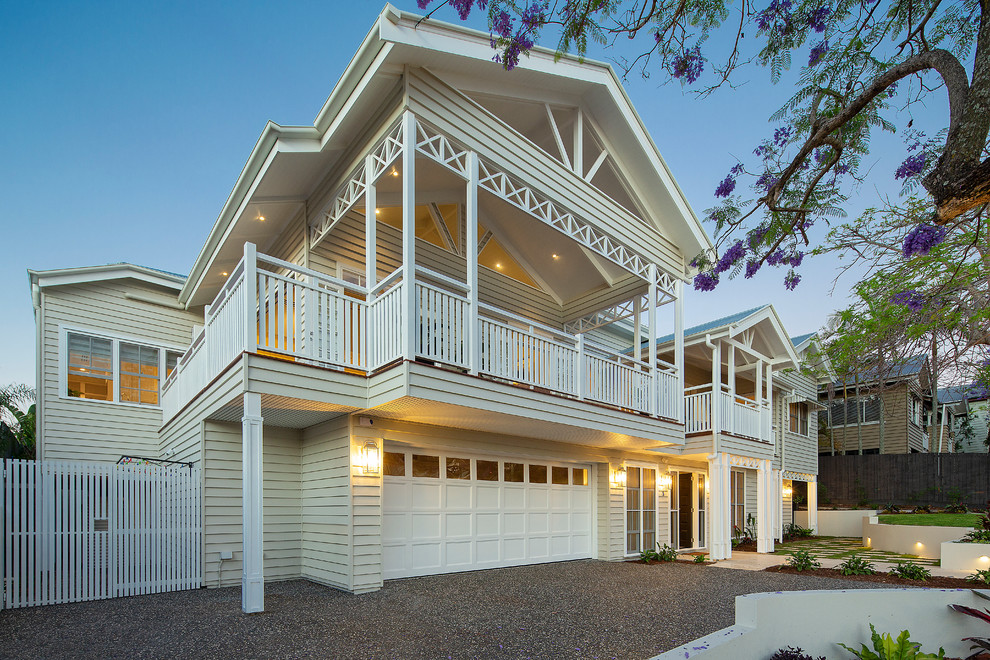 Photo of a large beach style two-storey beige house exterior in Brisbane with wood siding, a gable roof and a metal roof.