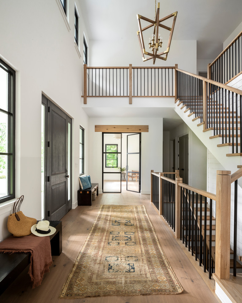 Transitional foyer in New York with white walls, light hardwood floors, a single front door and a dark wood front door.