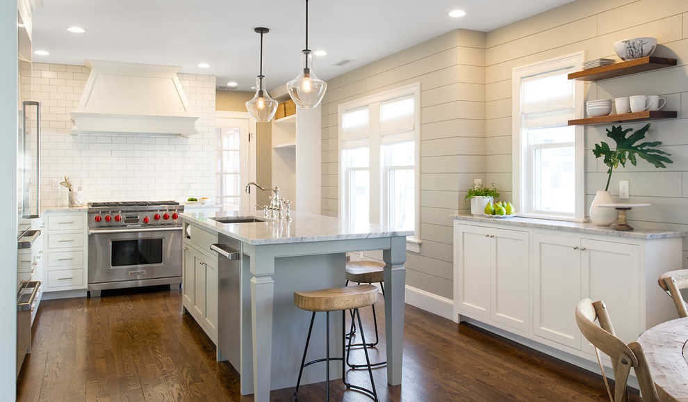 This is an example of a large transitional galley eat-in kitchen in Boston with a farmhouse sink, shaker cabinets, white cabinets, soapstone benchtops, white splashback, ceramic splashback, stainless steel appliances, dark hardwood floors, with island, brown floor and multi-coloured benchtop.