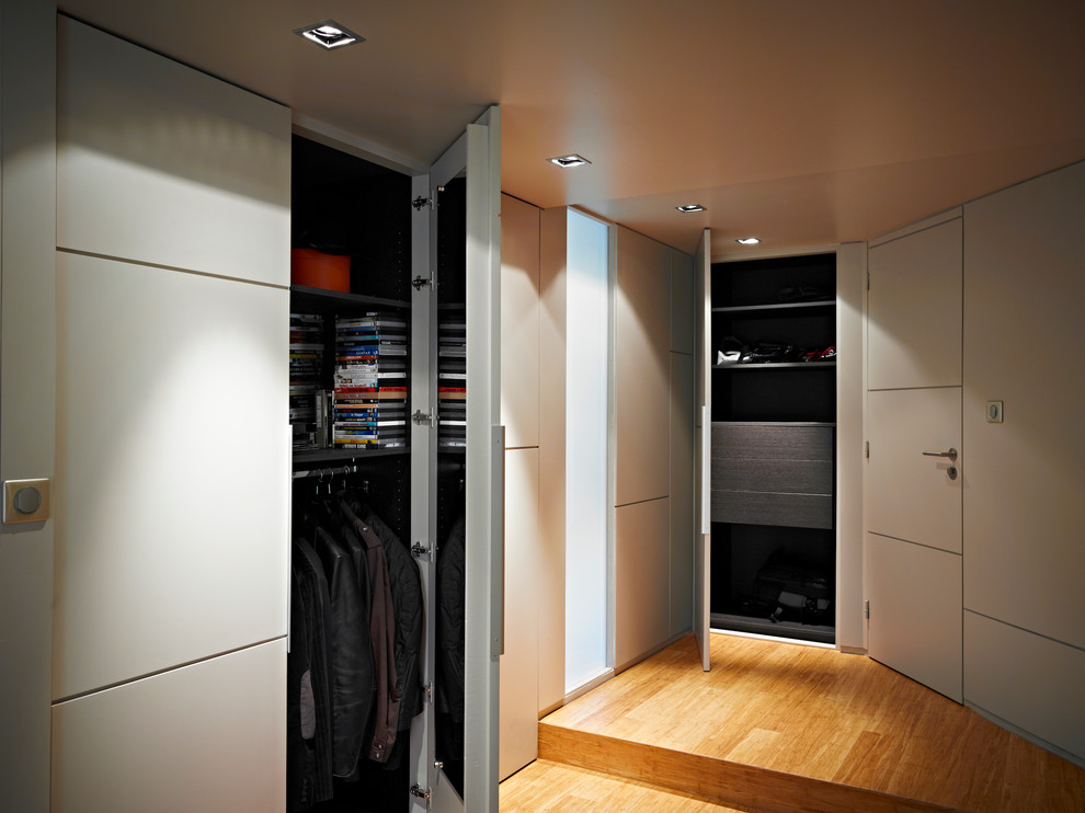 Mid-sized contemporary gender-neutral dressing room in Rennes with beaded inset cabinets, beige cabinets and bamboo floors.