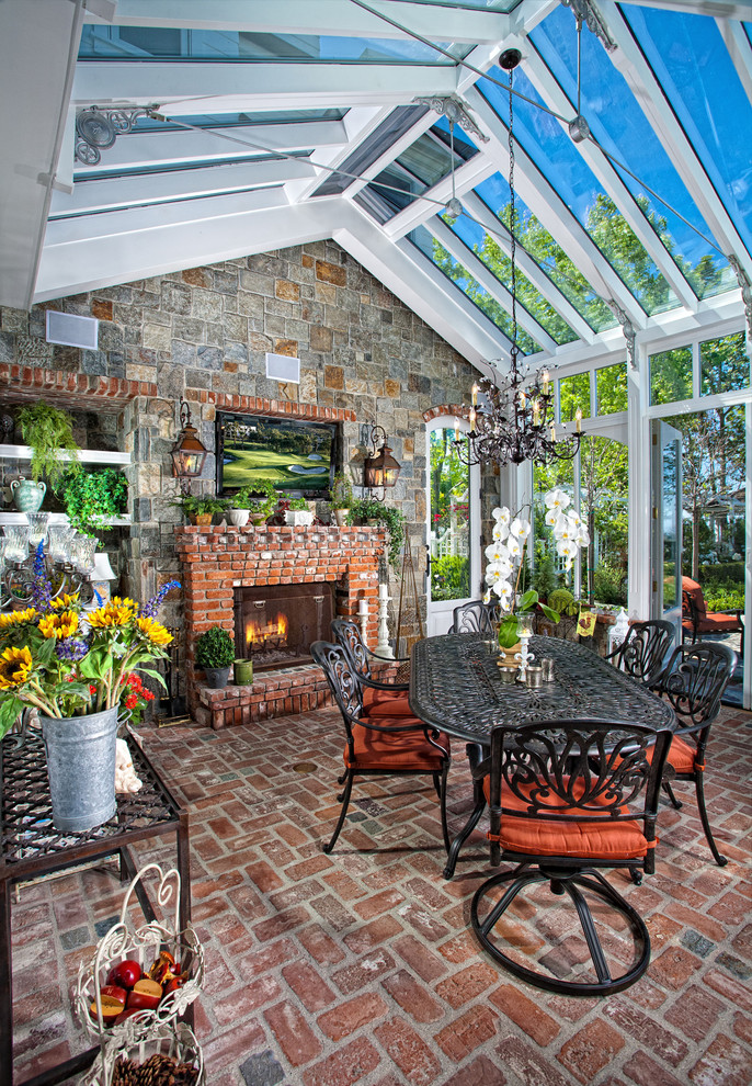 Photo of a traditional sunroom in Orange County with brick floors, a brick fireplace surround, a glass ceiling and red floor.