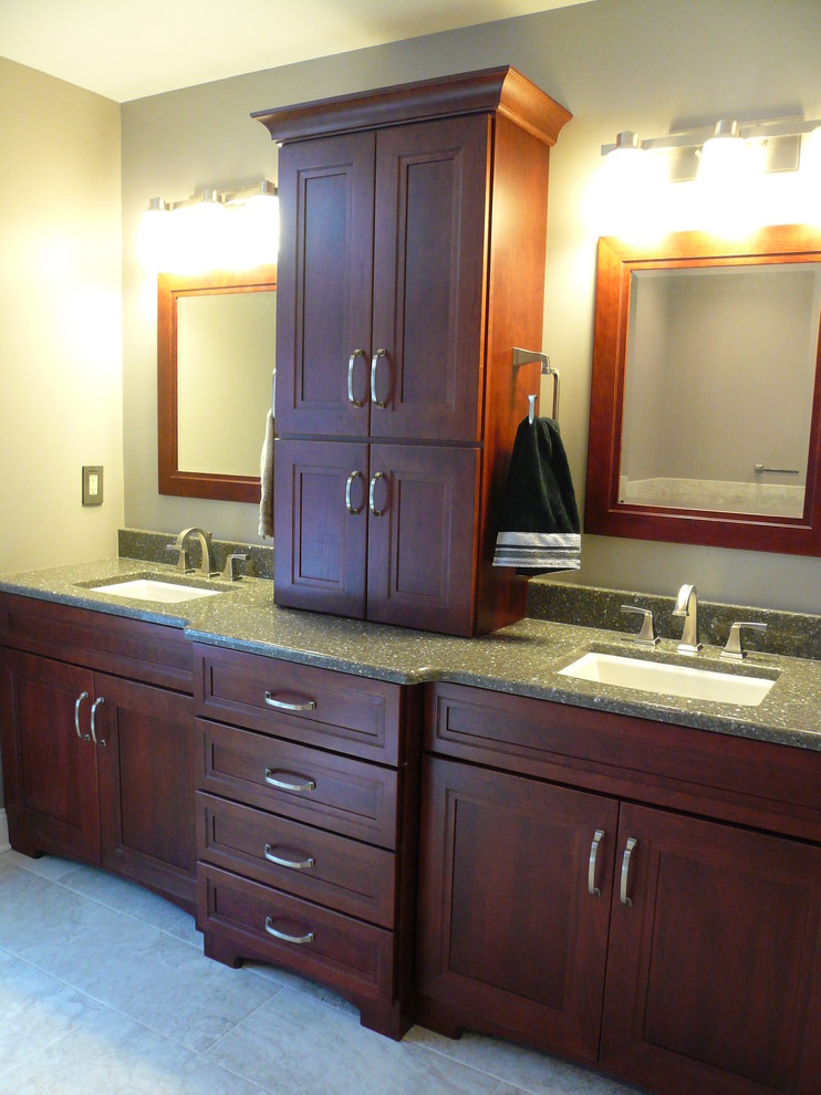 Example of a transitional master gray tile and porcelain tile porcelain tile and gray floor drop-in bathtub design with flat-panel cabinets, brown cabinets, a two-piece toilet, gray walls, an undermount sink, quartzite countertops and a hinged shower door