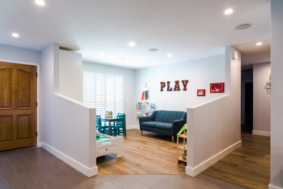 Mid-sized modern gender-neutral kids' playroom in Phoenix with white walls, medium hardwood floors and brown floor for kids 4-10 years old.