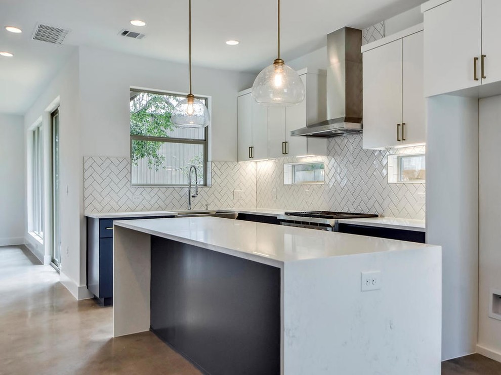 This is an example of a mid-sized modern l-shaped open plan kitchen in Austin with a farmhouse sink, flat-panel cabinets, white cabinets, marble benchtops, grey splashback, porcelain splashback, stainless steel appliances, concrete floors, with island, grey floor and white benchtop.