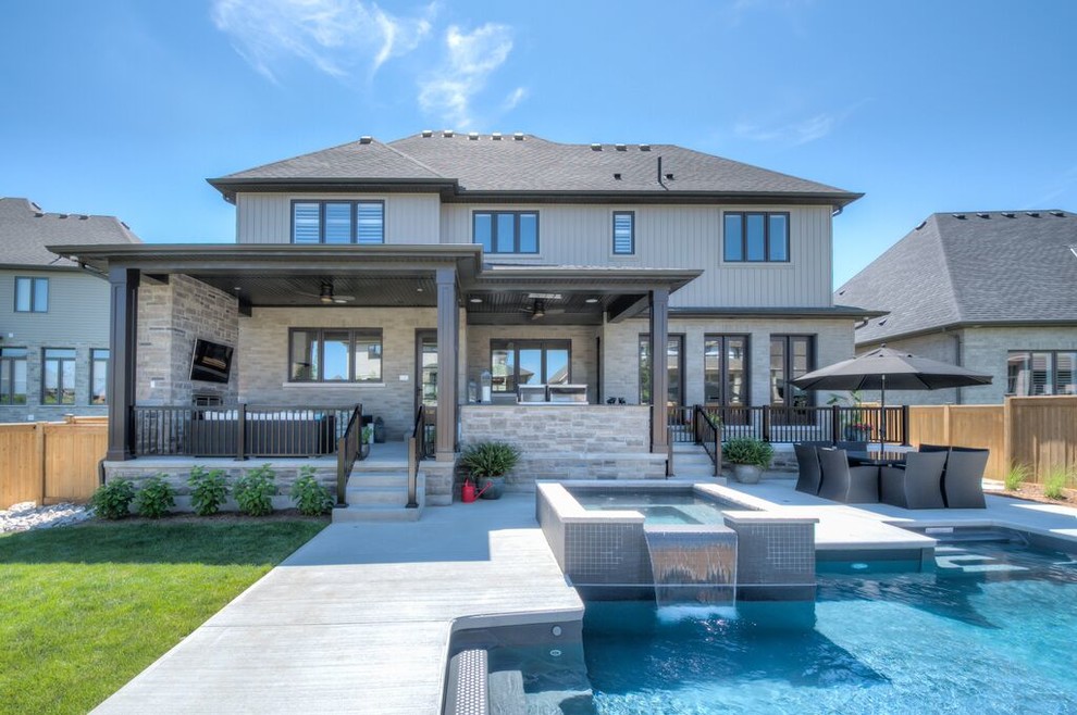 Large two-story and backyard mixed siding, concrete and rectangular hot tub photo in Toronto