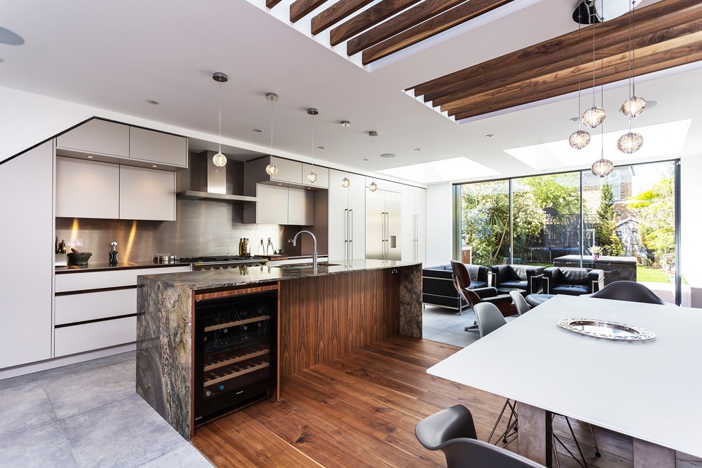 This is an example of a mid-sized contemporary galley open plan kitchen in London with an undermount sink, flat-panel cabinets, white cabinets, quartzite benchtops, metallic splashback, stainless steel appliances, porcelain floors, with island, grey floor and grey benchtop.