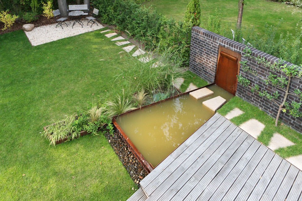 Idées déco pour un petit jardin à la française latéral moderne avec une cascade et une terrasse en bois.