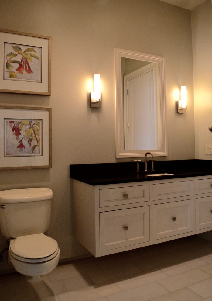 Example of a transitional travertine floor alcove shower design with an undermount sink, white cabinets, granite countertops, gray walls, flat-panel cabinets and a wall-mount toilet