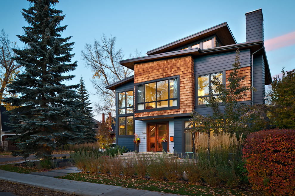 Design ideas for a large contemporary two-storey grey exterior in Calgary with vinyl siding and a flat roof.