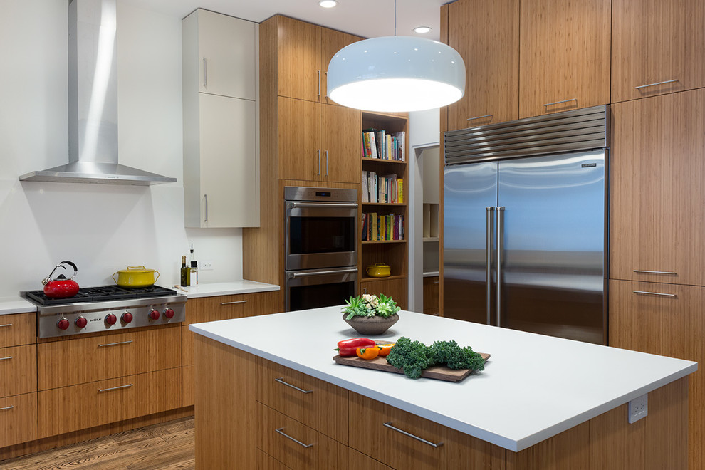 Inspiration for a mid-sized contemporary kitchen in New York with flat-panel cabinets, medium wood cabinets, quartz benchtops, white splashback, stainless steel appliances, medium hardwood floors and with island.