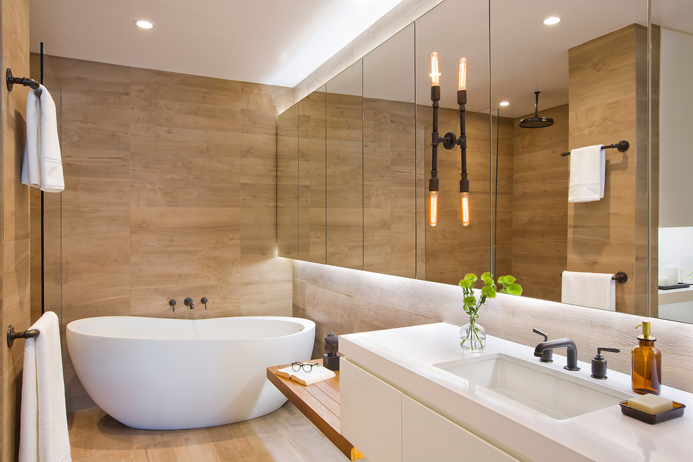 This is an example of a mid-sized contemporary master bathroom in Los Angeles with an undermount sink, a freestanding tub, flat-panel cabinets, white cabinets, brown walls, light hardwood floors and solid surface benchtops.