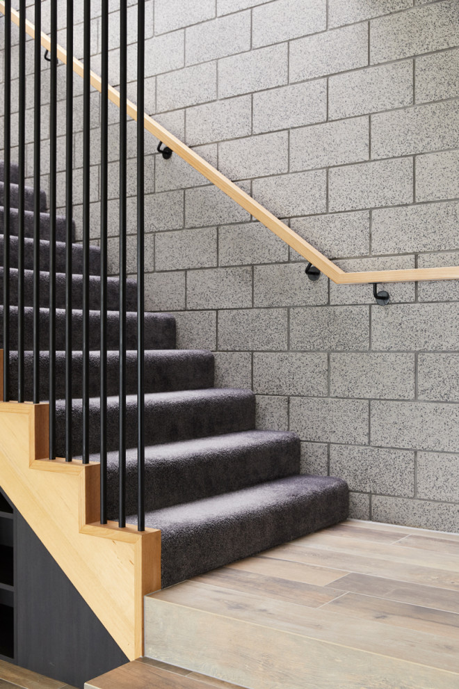 メルボルンにある中くらいなコンテンポラリースタイルのおしゃれなかね折れ階段 (カーペット張りの蹴込み板、木材の手すり、レンガ壁) の写真
