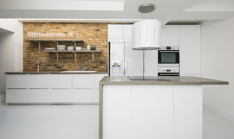 Inspiration for a large classic open plan kitchen in London with a built-in sink, flat-panel cabinets, white cabinets, granite worktops, yellow splashback, white appliances, concrete flooring and an island.