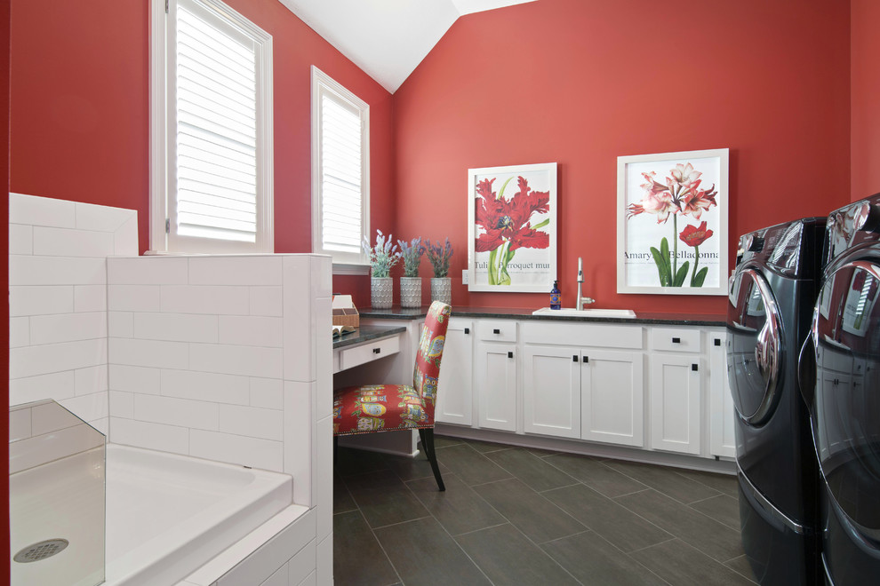 Inspiration for a transitional laundry room in Indianapolis with a drop-in sink, shaker cabinets, yellow cabinets, red walls, grey floor and black benchtop.