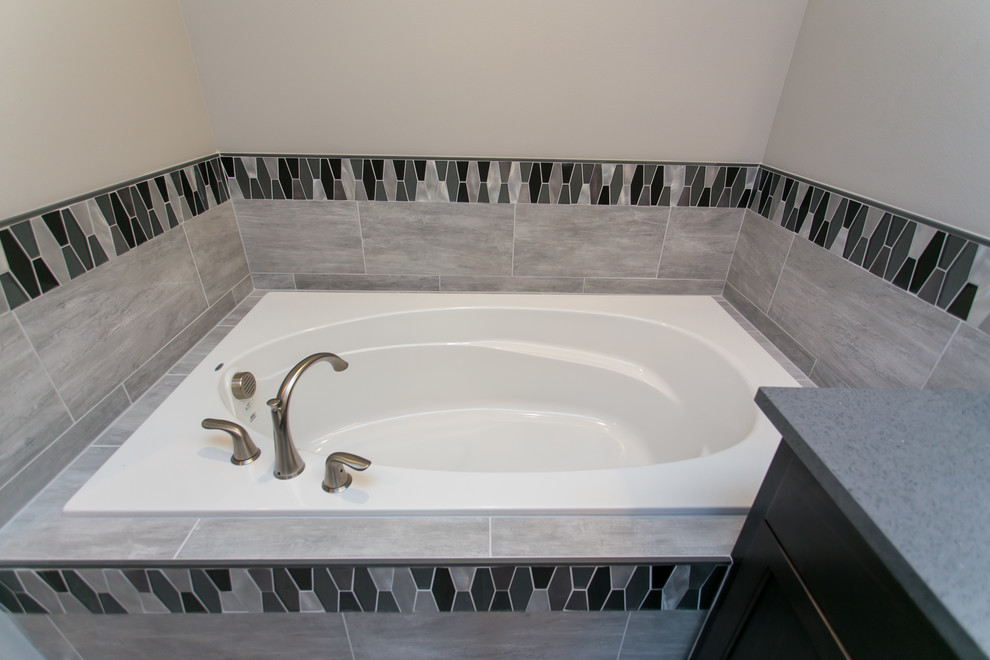 Inspiration for a mid-sized transitional master bathroom in Seattle with shaker cabinets, dark wood cabinets, a drop-in tub, an open shower, a two-piece toilet, gray tile, glass tile, grey walls, porcelain floors, an undermount sink, engineered quartz benchtops, grey floor and an open shower.