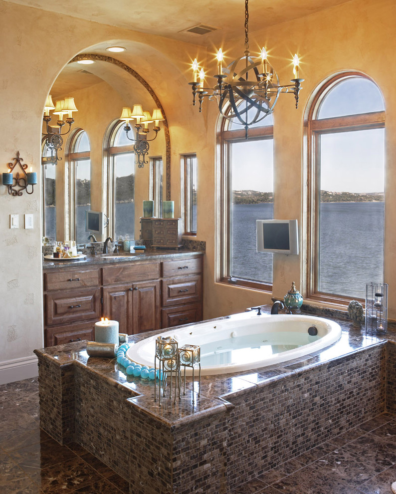 Design ideas for a large mediterranean master bathroom in Austin with raised-panel cabinets, dark wood cabinets, a drop-in tub, brown tile, brown walls, marble floors, an undermount sink, brown floor and brown benchtops.