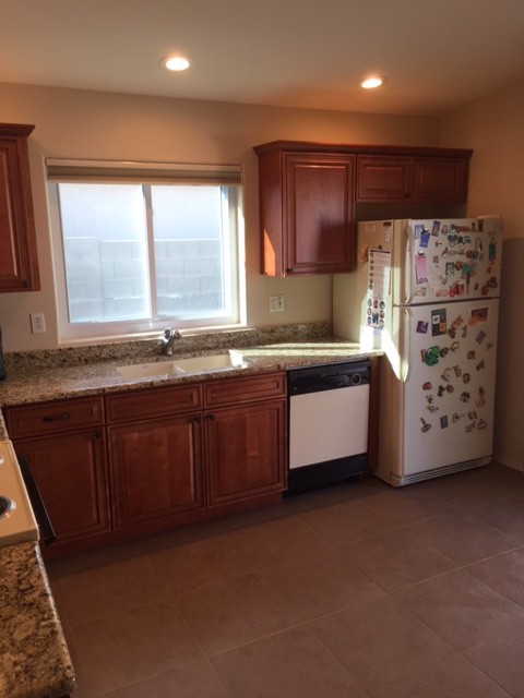 Small transitional l-shaped ceramic tile eat-in kitchen photo in Phoenix with an undermount sink, raised-panel cabinets, medium tone wood cabinets, granite countertops, white appliances and no island