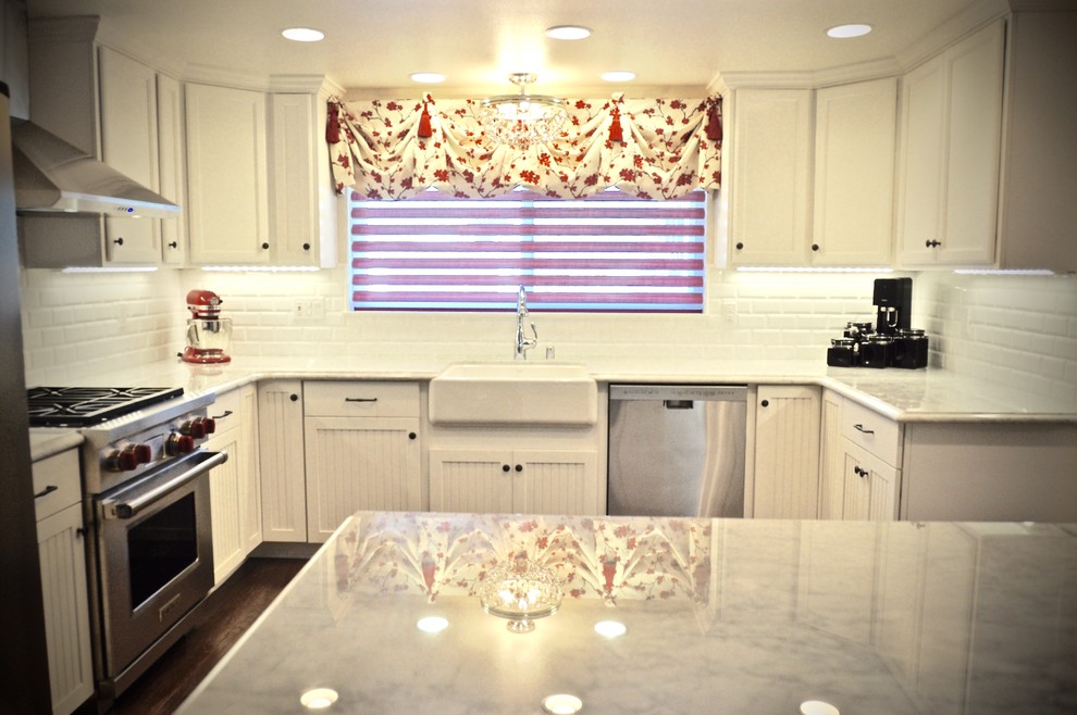 Photo of a traditional u-shaped eat-in kitchen in San Diego with a farmhouse sink, beaded inset cabinets, white cabinets, marble benchtops, red splashback, glass tile splashback, stainless steel appliances, medium hardwood floors and a peninsula.