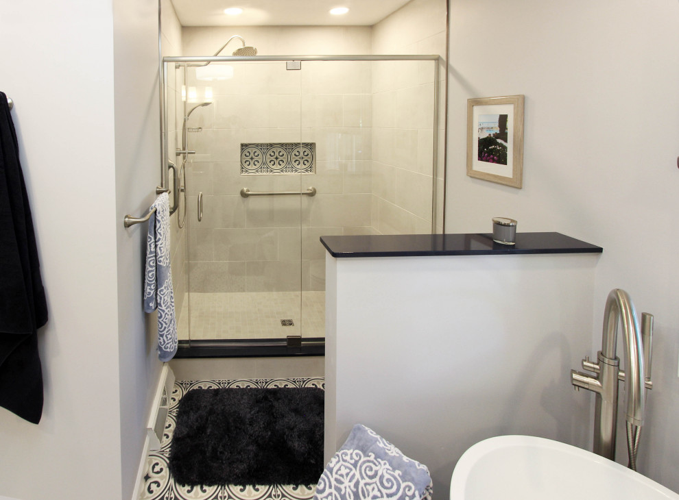 Photo of a mid-sized transitional master bathroom in Cleveland with flat-panel cabinets, grey cabinets, a freestanding tub, a corner shower, a two-piece toilet, gray tile, subway tile, grey walls, limestone floors, an undermount sink, engineered quartz benchtops, blue floor, a hinged shower door and blue benchtops.