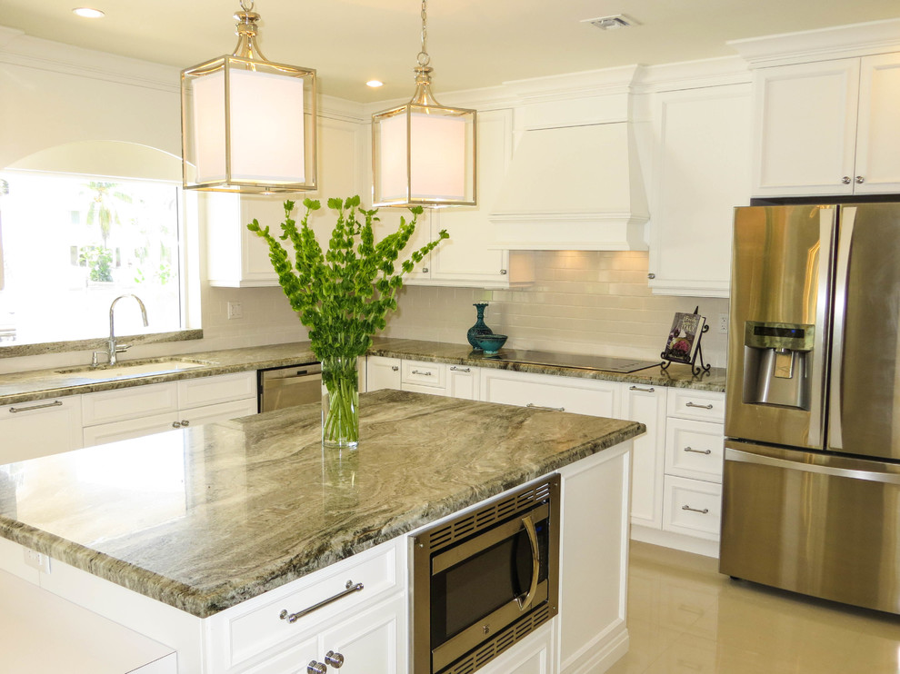 Large transitional u-shaped eat-in kitchen in Miami with a farmhouse sink, raised-panel cabinets, white cabinets, granite benchtops, white splashback, subway tile splashback, stainless steel appliances, porcelain floors and with island.