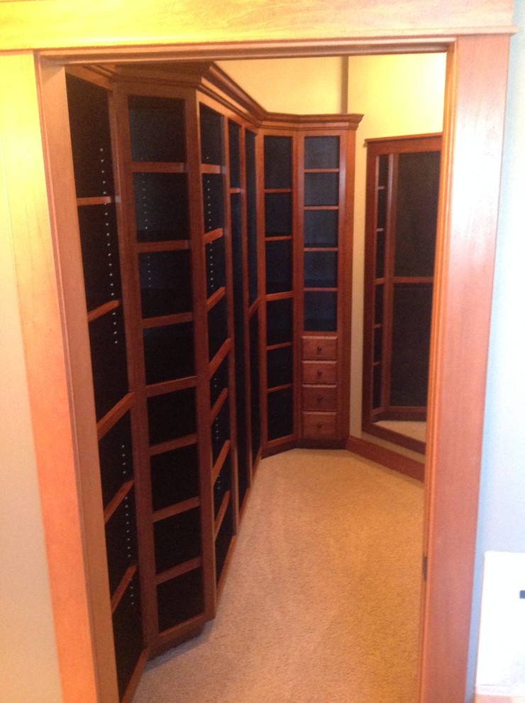 This is an example of a large gender-neutral walk-in wardrobe in Other with beaded inset cabinets, dark wood cabinets and carpet.