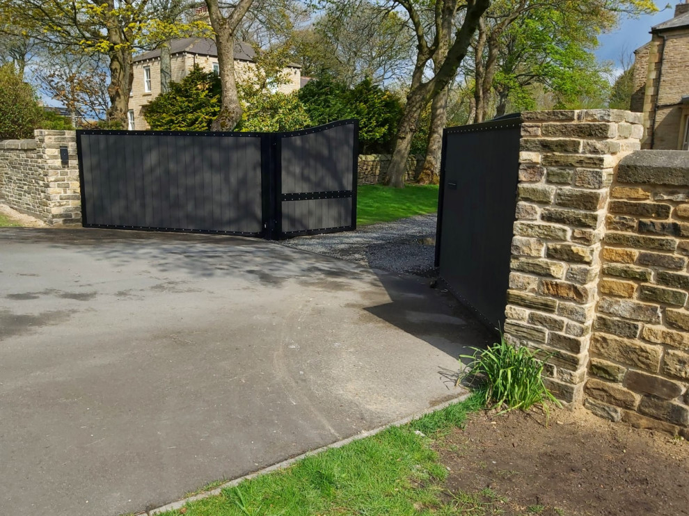 Medium sized traditional front driveway garden in Other with a stone fence and gravel.